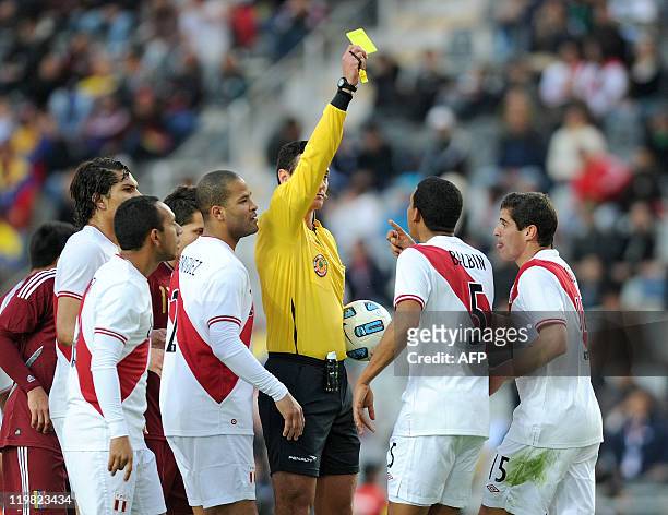 Colombian referee Wilmar Roldan shows a yellow card to Peruvian midfielder Adan Balbin during the 2011 Copa America football tournament third-place...