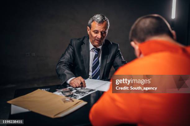 detective and prisoner in orange jumpsuit in interrogation room - probation stock pictures, royalty-free photos & images