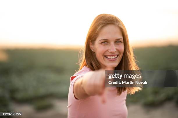 smiling young model with silky hair, bokeh shot. - pointing finger stock-fotos und bilder