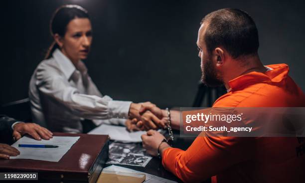 male prisoner shaking hand with lady lawyer in interrogation room - probation stock pictures, royalty-free photos & images