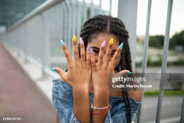 model on city bridge posing with colorful nails - fingernagel stock-fotos und bilder