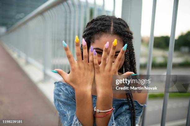 model on city bridge posing with colorful nails - fingernail stockfoto's en -beelden