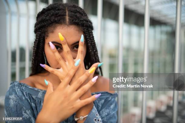 woman covering face with hand and staring at you - multi coloured nails stock pictures, royalty-free photos & images