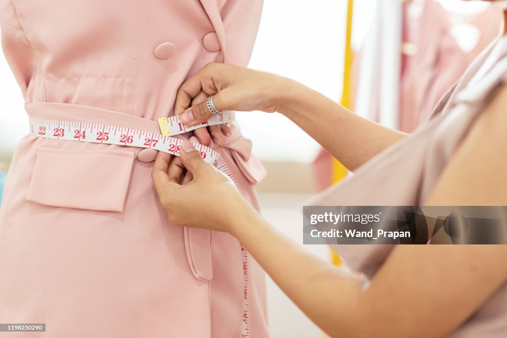 Close up hands Lifestyle Stylish tailor taking measurements on mannequin in studio. Woman fashion designer working on her design in the showroom, Business small Concept