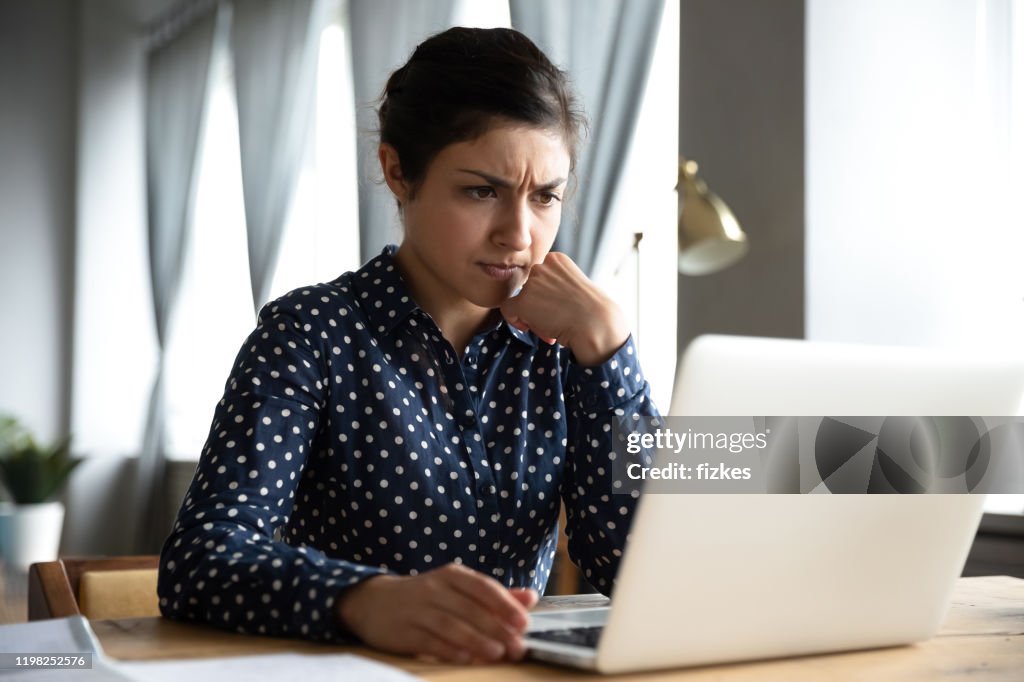 Concerned indian woman look at laptop frustrated about computer problem