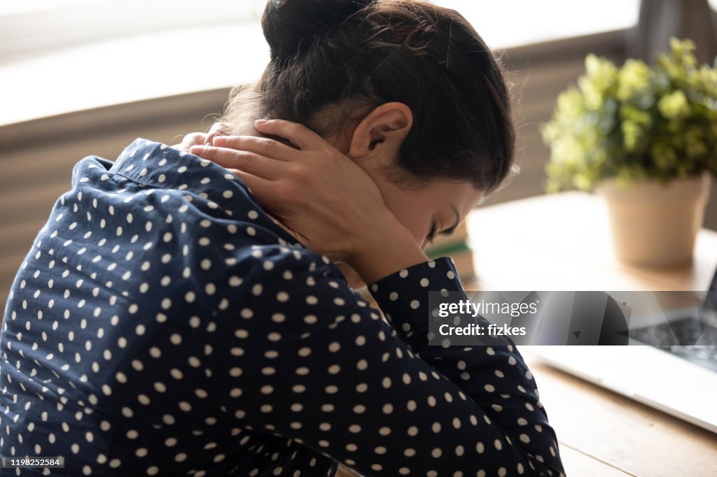 Mujer india fatigada siente dolor de cuello cansado del trabajo de la computadora