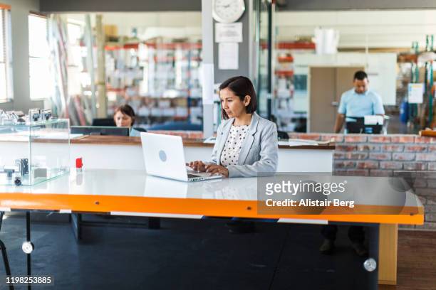 female business woman in open plan office of a small business - open laptop on desk stock-fotos und bilder