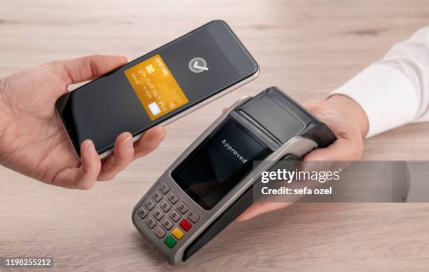 contactloos betalen met smartphone op het verkooppunt - hand holding credit card and phone stockfoto's en -beelden