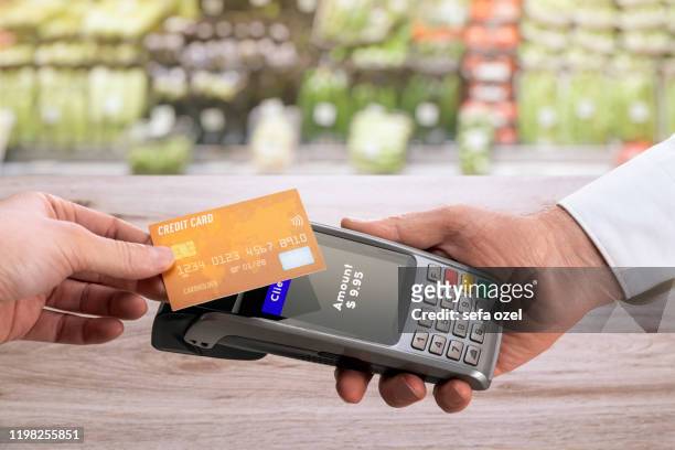 kontaktloses bezahlen mit kreditkarte im lebensmittelgeschäft - poes stock-fotos und bilder