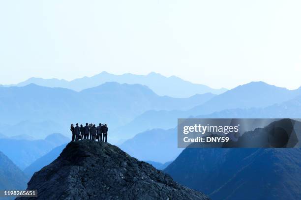 group of business people standing at top of mountain top - teamwork mountain stock pictures, royalty-free photos & images