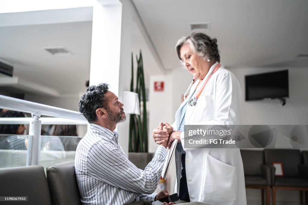 Female doctor consoling sad man at hospital