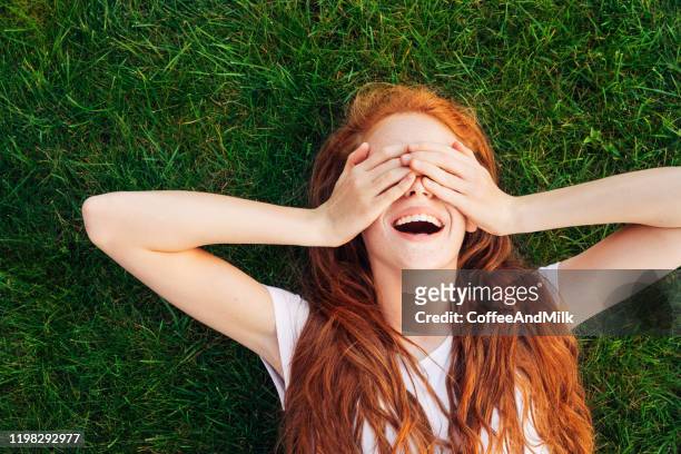teenage girl laying on the grass - women lying imagens e fotografias de stock