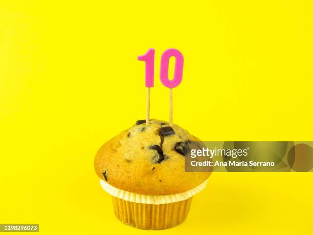 10th birthday candles in a cupcake with chocolate pieces on a yellow background - 10th birthday cakes stock pictures, royalty-free photos & images