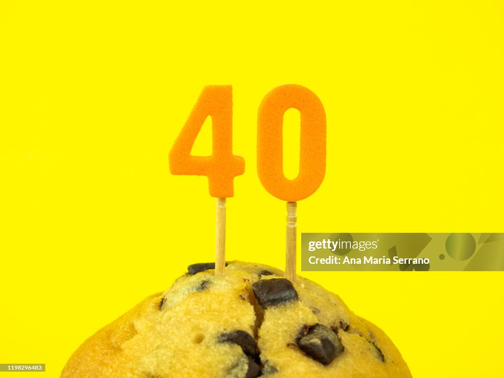 40th Birthday candles in a cupcake with chocolate pieces on a yellow background