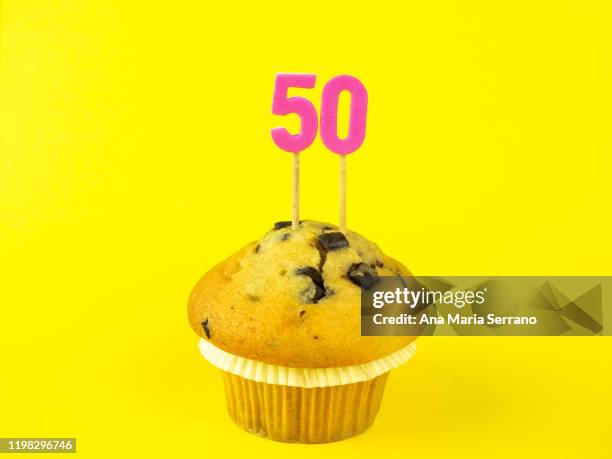 50th birthday candles in a cupcake with chocolate pieces on a yellow background - zahl 50 stock-fotos und bilder