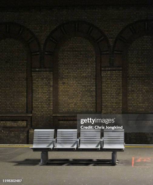 bench on platform against brick wall - binario di stazione ferroviaria foto e immagini stock