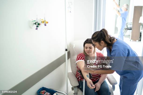 women receives iv drip treatment - iv going into an arm stock pictures, royalty-free photos & images