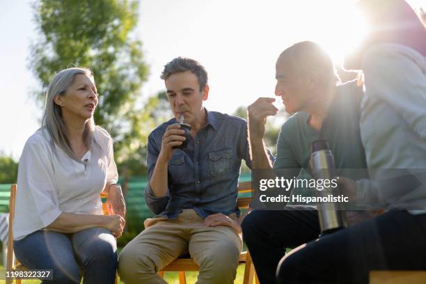 hombre adulto bebiendo compañero mientras disfruta de una tarde con sus padres mayores y su esposa fuera - yerba mate fotografías e imágenes de stock