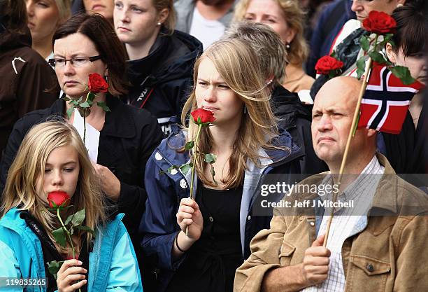 Mourners hold roses, part of an estimated 100,000 people gather in Oslo town centre for a vigil following Friday's twin extremist attacks on July 25,...