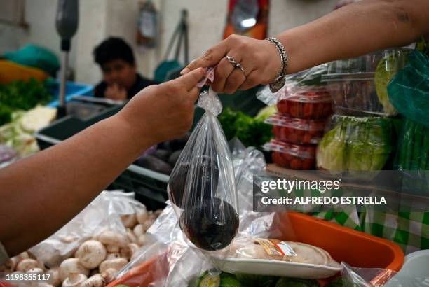 Street vendor delivers avocado on a plastic bag at the Juarez market in Mexico City, on January 15, 2020. Since January 1 the Mexican capital...