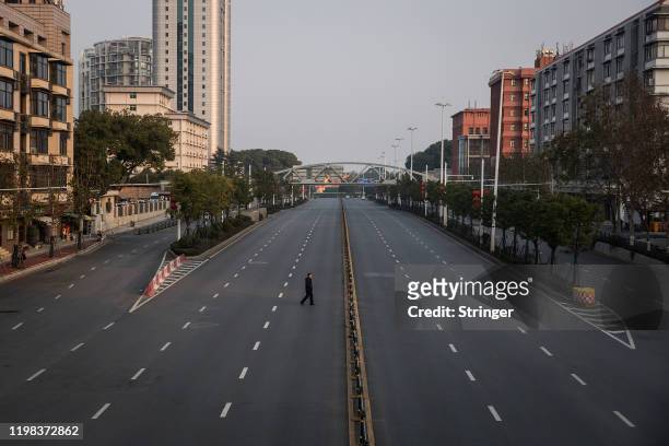 Man cross an empty highway road on February 3, 2020 in Wuhan, Hubei province, China. The number of those who have died from the Wuhan coronavirus,...