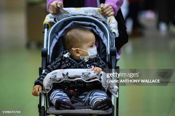 Baby wearing a protective face mask is pushed by a woman as they arrive from Shenzhen to Hong Kong at Lo Wu MTR station, hours before the closing of...