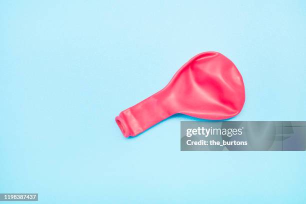 pink deflated balloon on blue background - balloon burst stock pictures, royalty-free photos & images