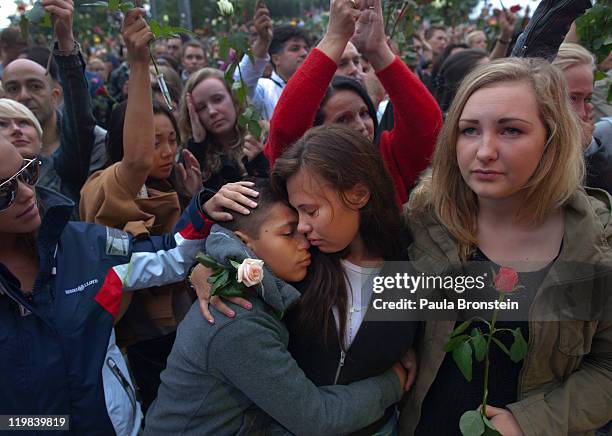 Norwegians hold roses and confort each other as thousands of people gather at a memorial vigil following Friday's twin extremist attacks on July 25...