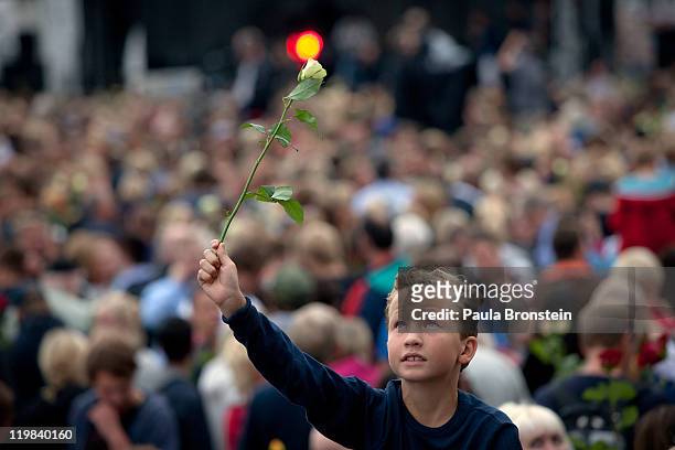 Boy holds up a rose as hundreds of thousands of people gather at a memorial vigil following Friday's twin extremist attacks, July 25, 2011 in Oslo,...