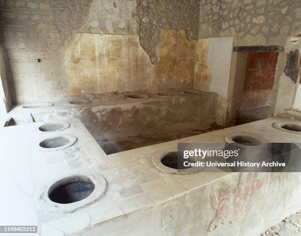 Italy. Pompeii. Ancient Roman city destroyed by the eruption of the Vesuvius in 79 AD. Bar counter with holes where jars were set into them for food...