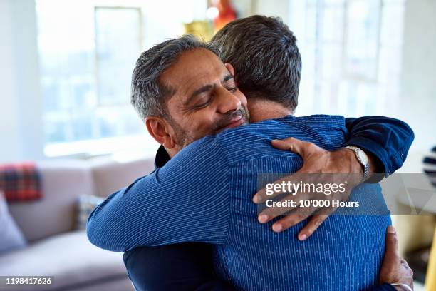 candid portrait of mature male friends hugging - abrazo fotografías e imágenes de stock