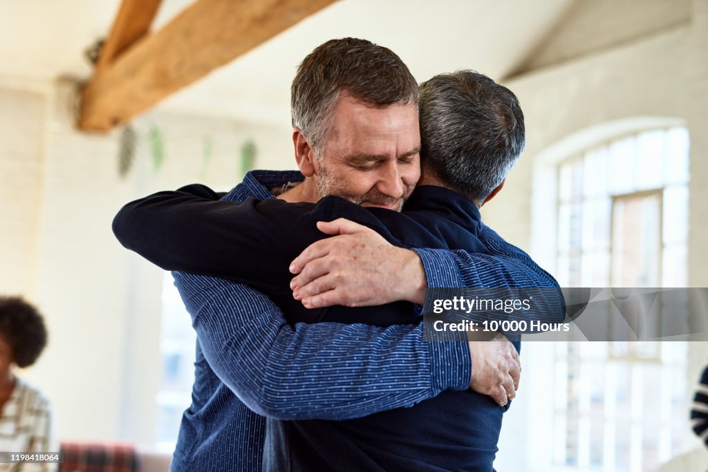 Portrait of mature friends embracing with arms around each other