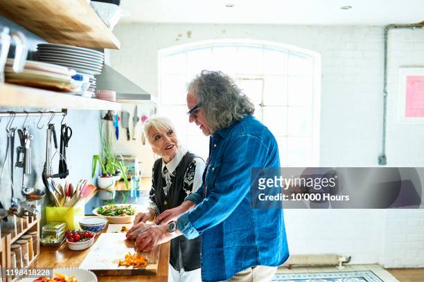 senior couple cooking healthy food together at home - alter mann kocht stock-fotos und bilder