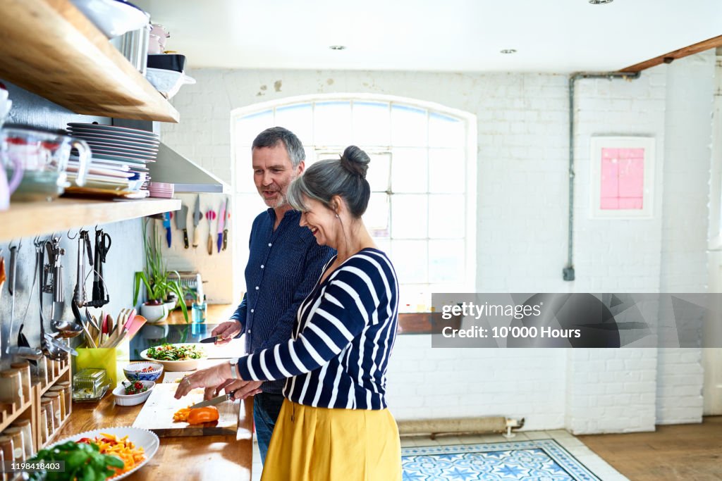 Mature couple preparing vegetarian meal in stylish kitchen