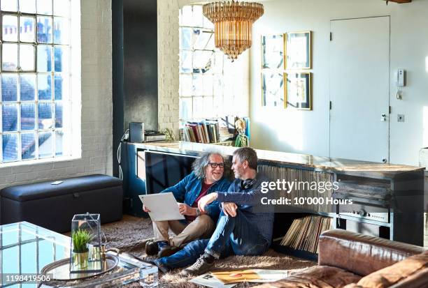 male friends sitting on floor discussing record collection - apartamento tipo loft imagens e fotografias de stock