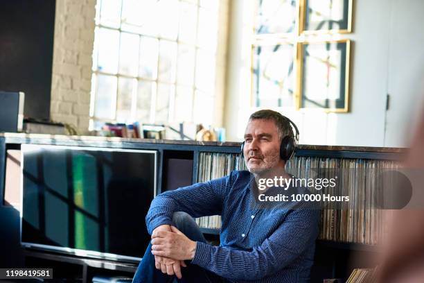 mature man wearing headphones and looking thoughtful - record music stock pictures, royalty-free photos & images