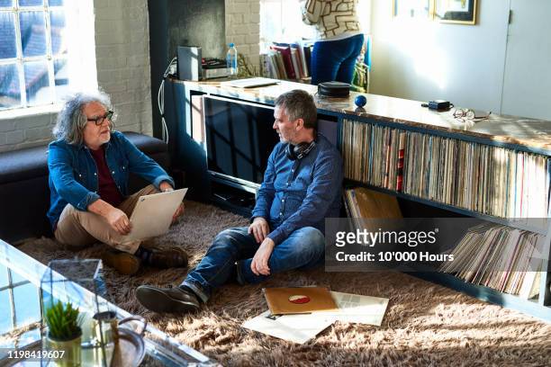 two men sitting on floor looking at record collection - collections stock-fotos und bilder