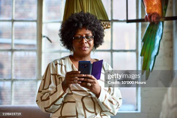 portrait of mature woman using smartphone at home - african on phone stock pictures, royalty-free photos & images