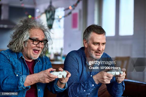 senior men playing computer games at home - gaming controller fotografías e imágenes de stock