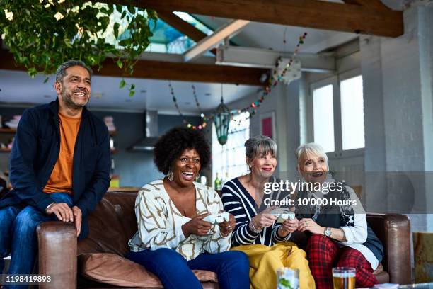 senior friends playing computer games together on sofa - silver surfer stock pictures, royalty-free photos & images