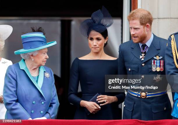 Queen Elizabeth II, Meghan, Duchess of Sussex and Prince Harry, Duke of Sussex watch a flypast to mark the centenary of the Royal Air Force from the...