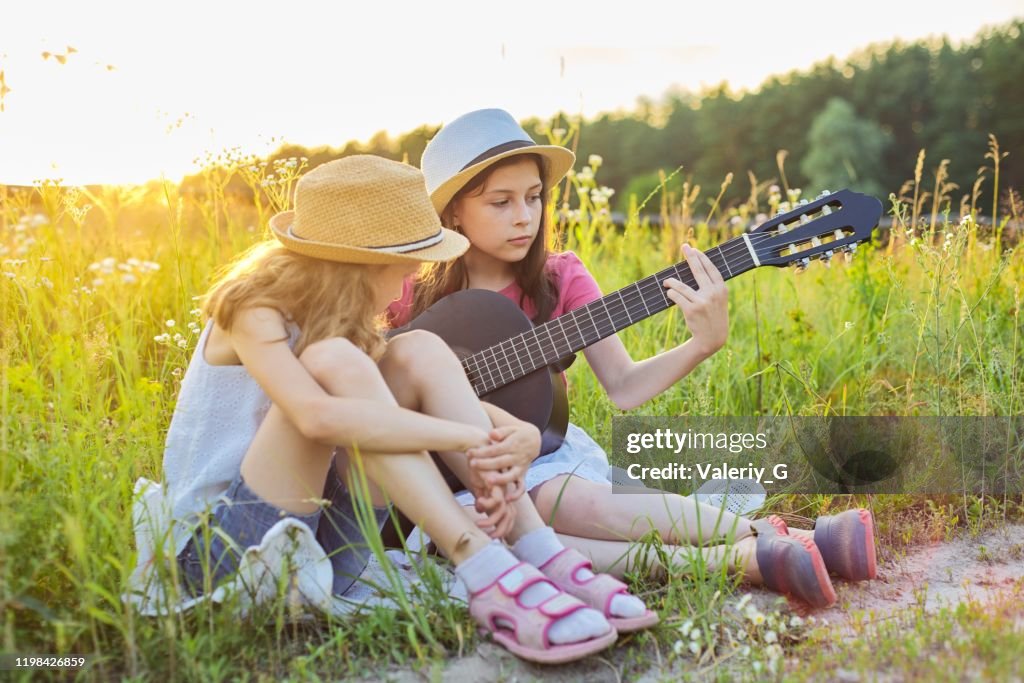 Barn som sitter i naturen med klassisk gitarr
