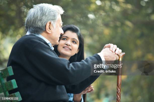 daughter with old father talking at public park - daughter stock pictures, royalty-free photos & images