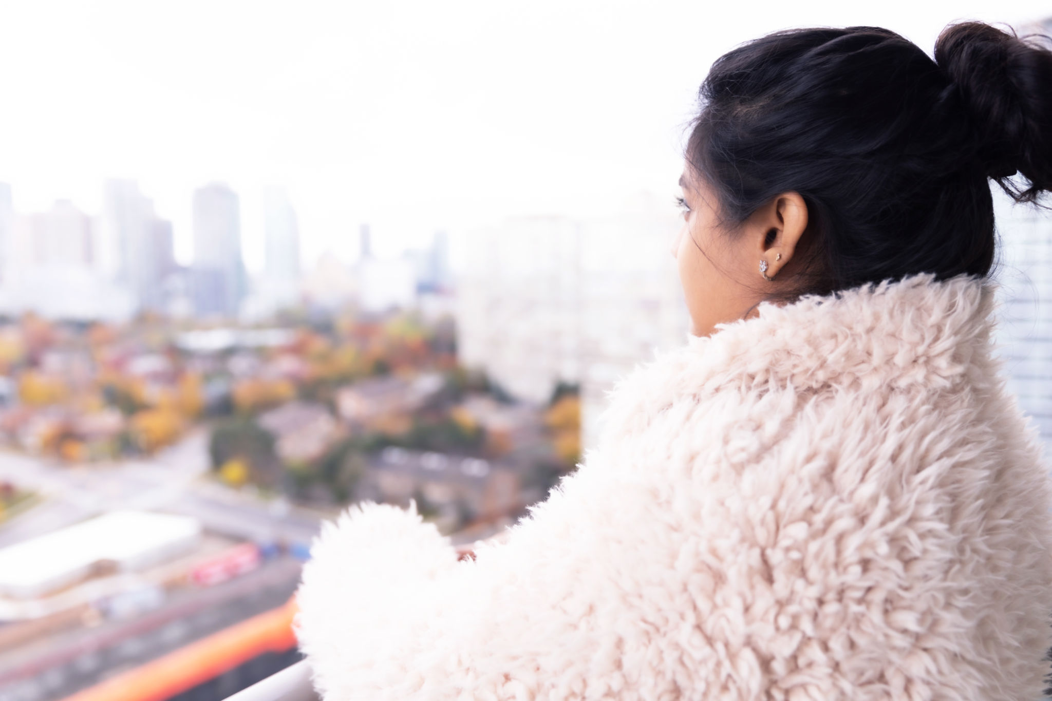 Girl standing at the balcony and admiring views from a highrise Girl standing at the balcony and admiring views from a highrise