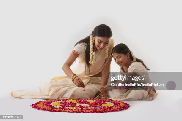 south indian woman making rangoli with her daughter - onam stock pictures, royalty-free photos & images