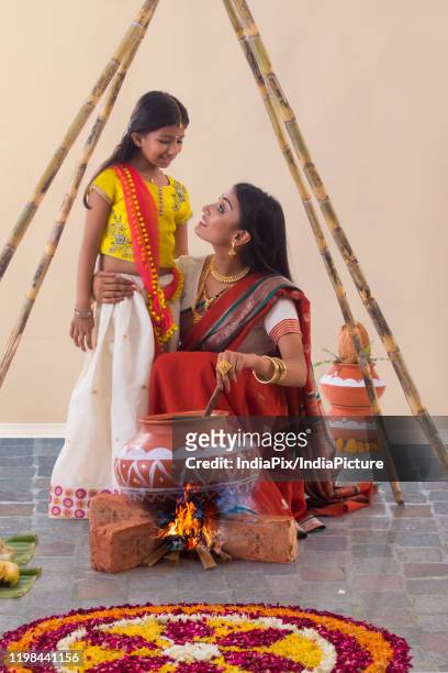 mother looking at her daughter while cooking food on pongal - pongal stockfoto's en -beelden