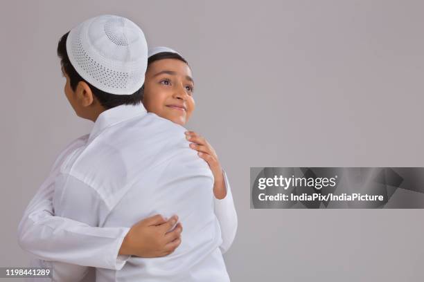 young muslim boys with caps hugging each other - skull cap stock pictures, royalty-free photos & images