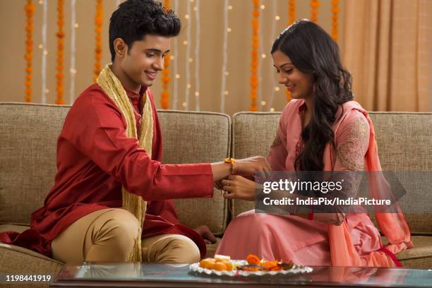 young girl tying rakhi to her brother on rakshabandhan - raksha bandhan stock-fotos und bilder