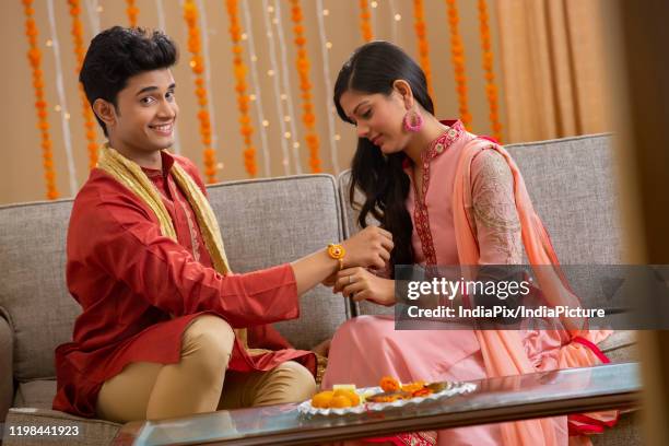 beautiful sister tying rakhi on her brother's wrist - akhi stock pictures, royalty-free photos & images