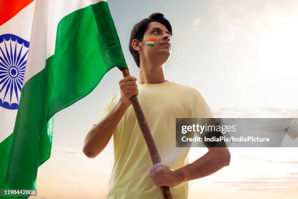 young man holding indian flag proudly, independence day - indian tricolor stock pictures, royalty-free photos & images